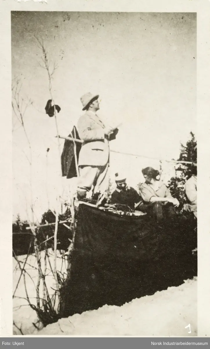 Sollirennet 1928. Mann står på en hjemmelaget tribune og holder noe i hendene, ved siden sitter publikum