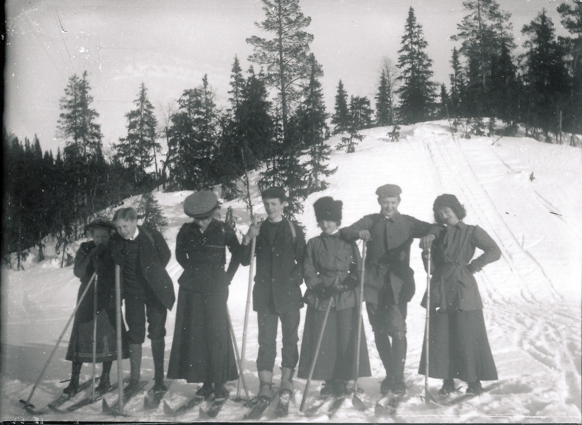 Medlemmer og venner av familien Rydgren på skitur. Fire unge kvinner og tre unge menn ved siden av hverandre på ski i skogsterreng. Harald Rydgren nr. 2 fra høyre.