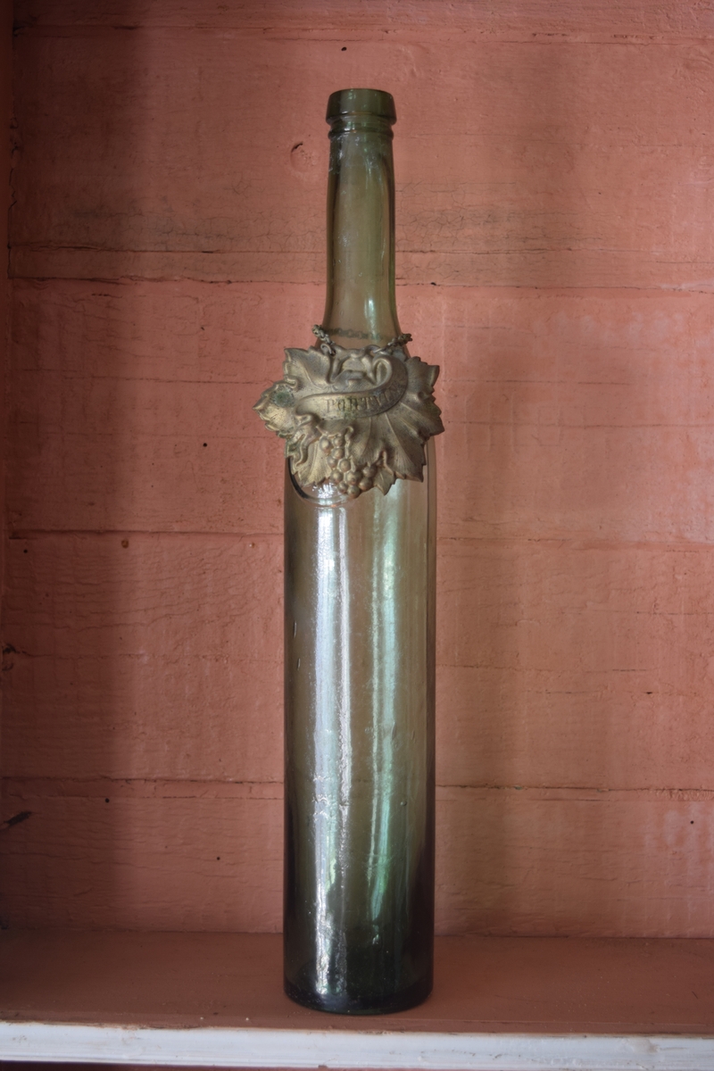 Vinflaske eller karaffel. Det er et grønnskjær i glasset og flasken er dekorert med en medaljong med påskriften "portvin"