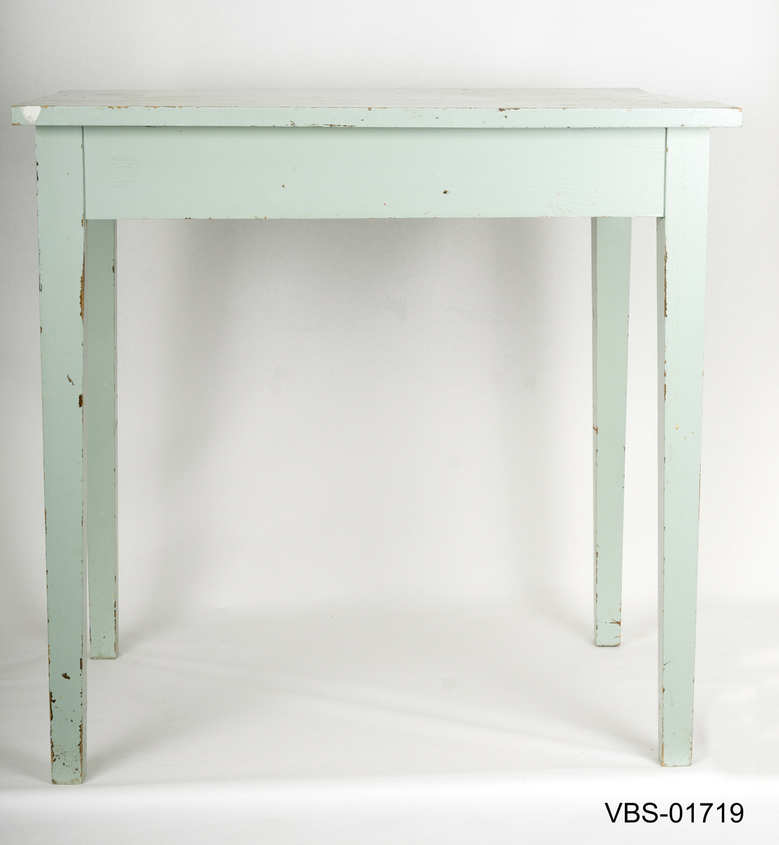 Enkelt bord med rette ben litt  avsmalnende nede. Håndverk arbeidsbord.
Bordplaten er laget av tre limte brett og med innvendige forsterkninger i hjørnene.