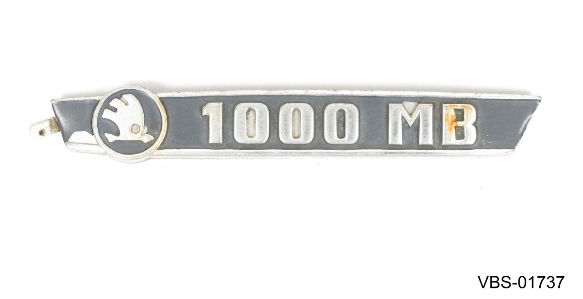 Bilskilt, eller bil emblem av Skoda. Merkelogo og preget tetning på -1000 MB- skiller seg ut mot den svartmalte bakgrunnen.