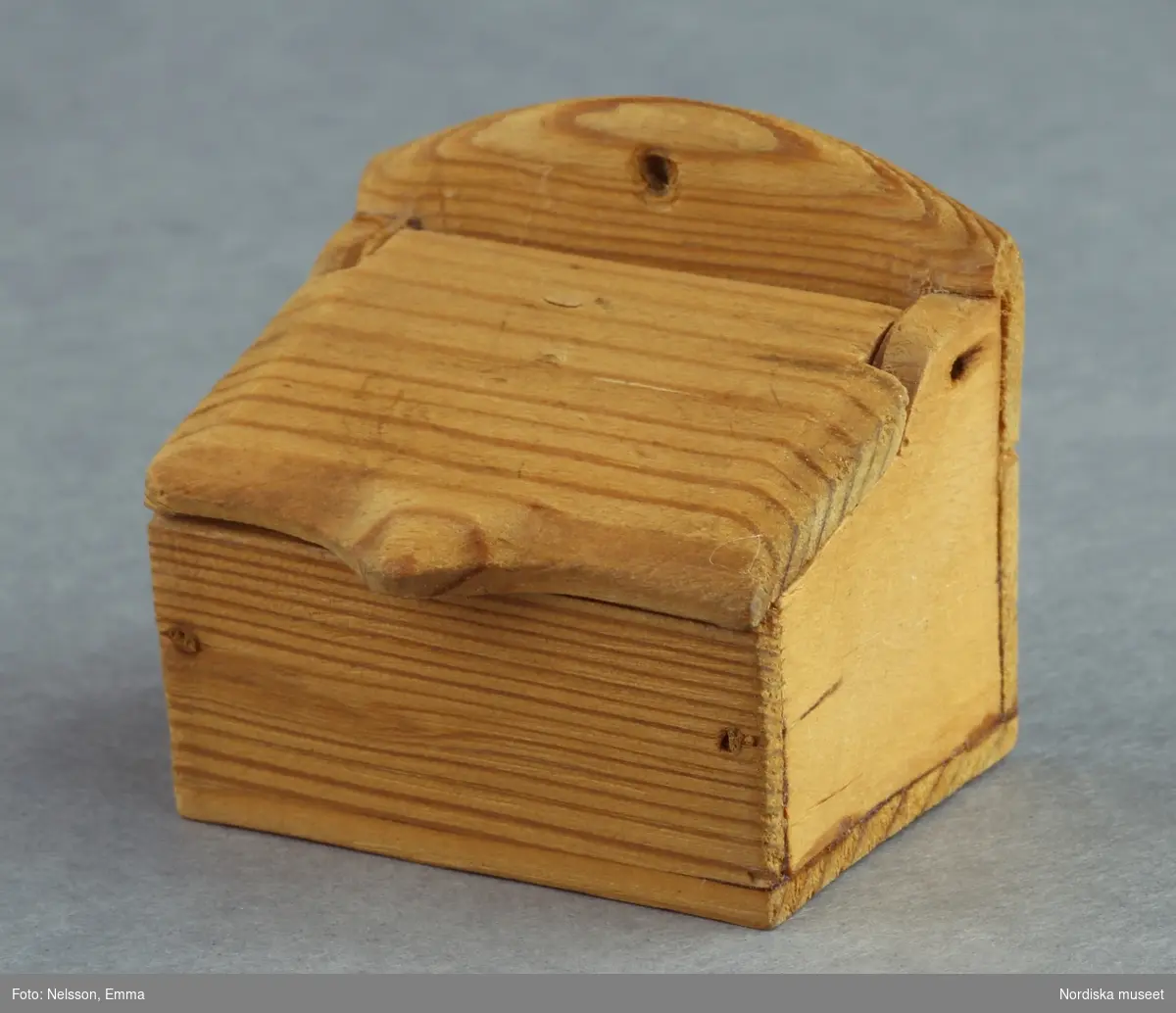 Inventering Sesam 1996-1999:
L 3,9 cm
B 2,8 cm
H 3,7 cm
Mjölkar till dockskåp, av obehandlat trä, rektangulär låda med öppningsbart snedlock och uppskjutande baksida. 
Tillhör dockskåp inv 164.570. Brukad av givarinnan, född 1886.
Leif Wallin nov 1997
