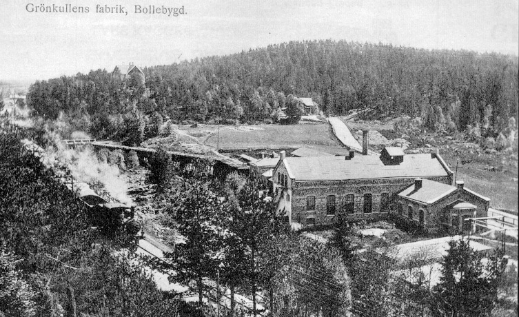 Tåget passerar Grönkullen, där det tidigare fanns en hållplats. Fabriken är nuvarande HP Färg & Kemi, och bilden är från tidigt 1900-tal.