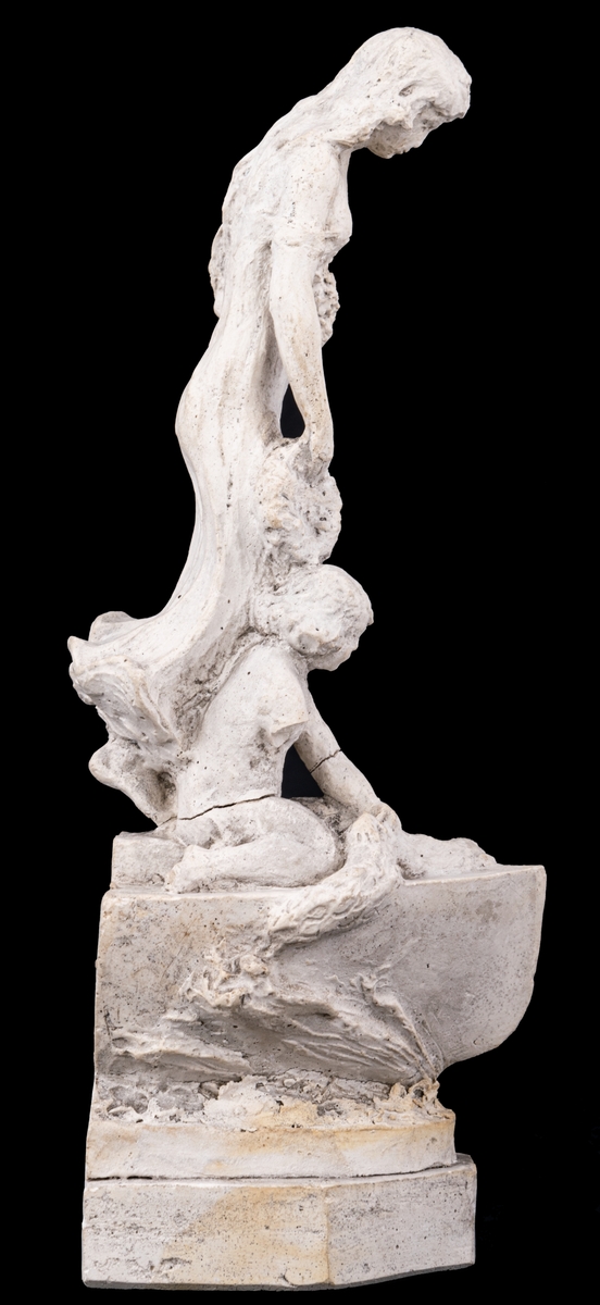 Skulpturskiss av Ida Matton, signerad Paris 1920, till gravmonument för redarfamiljen Brodin i Gävle. Kvinna med blommor i händerna med ett barn med blomgirlang sittande framför fötterna. Båda placerade på en trekantig sockel som liknar stäven på en båt.