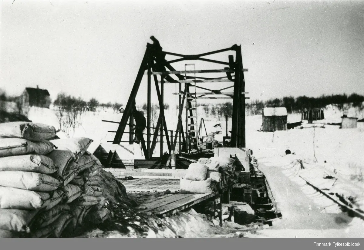 Her ser vi Munkelv bru under bygging, 1941. De sekkene vi ser helt til venstre er sement. Anlegg: Hesseng-Neiden. 