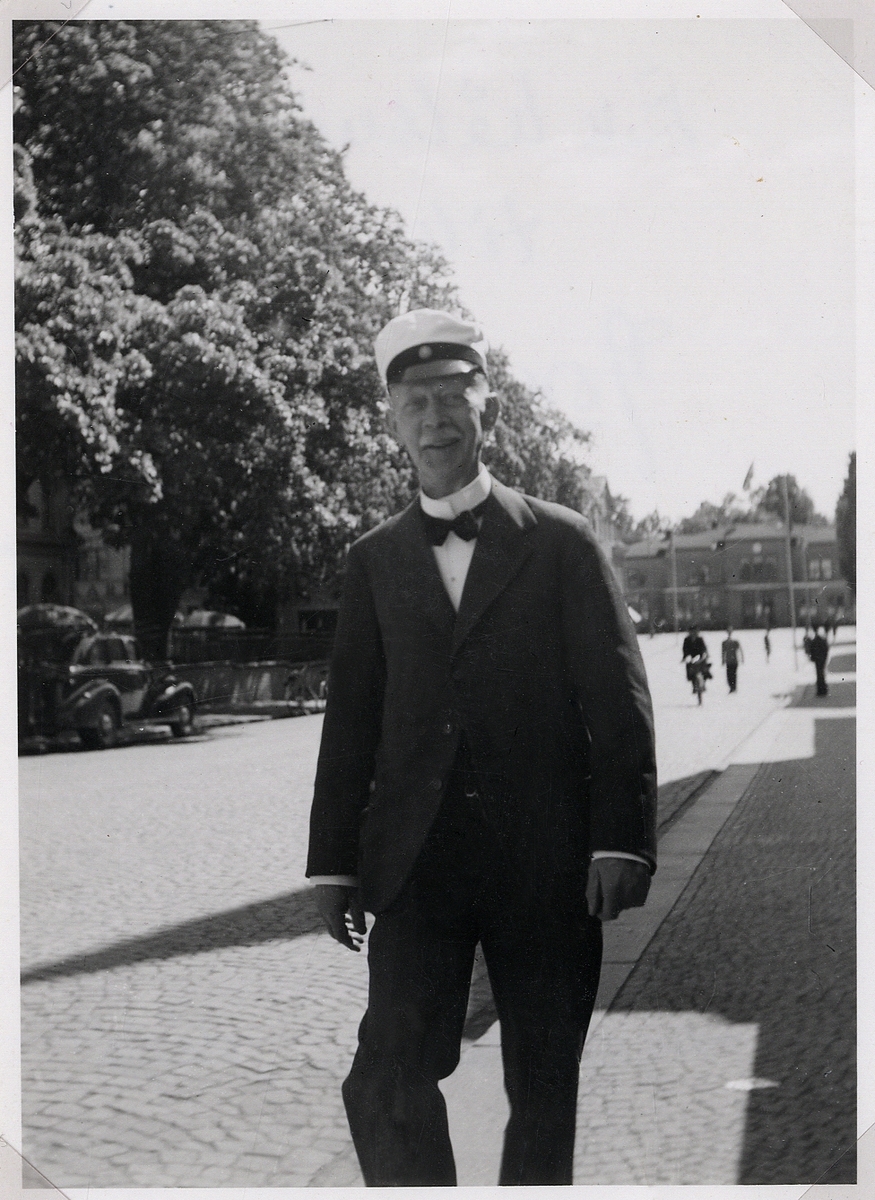 August Johnson ("Jonte"), läroverksadjunkt vid Växjö högre allmänna läroverk 1907-1932, på promenad längs Kungsgatan, ca 1940. 
I bakgrunden skymtar järnvägsstationen.