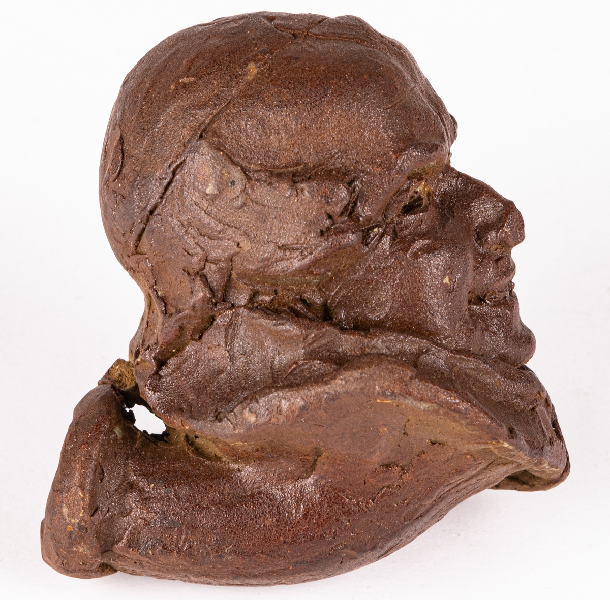 Skiss i lera till piphuvud, kort skaftstycke med huvud som leende manshuvud. Gjord av Ida Matton.