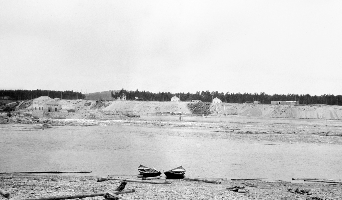 Den da forholdsvis nybygde kraftstasjonen ved Skjefstadfossen i Glomma, Heradsbygda i Elverum, Hedmark fotografert i 1916. Fotografiet er sannsynligvis tatt fra Tjuvholmen, sentralt i elveløpet, mot den vestre elvebredden. I forgrunnen var to robåter trukket opp på stranda. I bakgrunnen skimter vi noe tømmer på vannspeilet.
