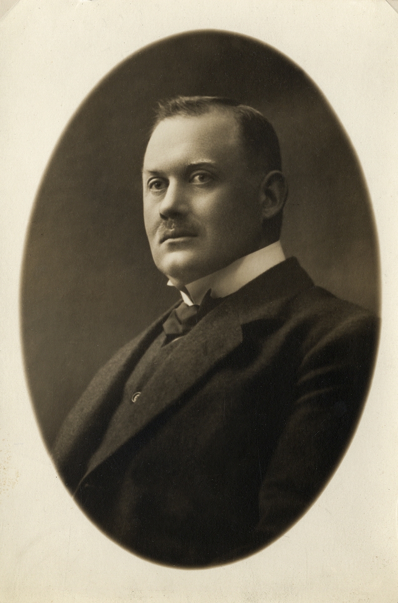 En man i kostym med väst, stärkkrage och fluga. Bröstbild, halvprofil.'
Ateljéfoto, ca 1920.