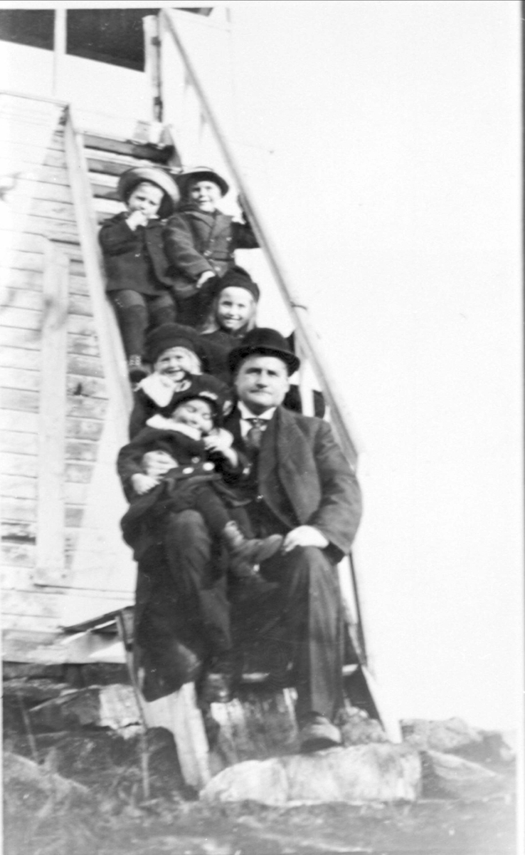 Johannes M. Andreassen med fem av barna sittende i trappen til utkikkstårnet i Kveldteigen.