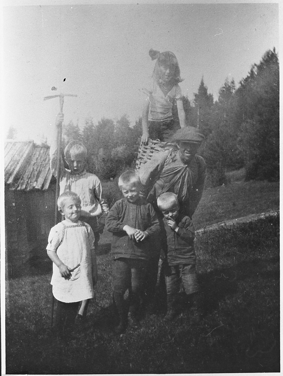 Engebret Flågan med teine på ryggen, omgitt av flere barn. Åsen på Grenskogen, 1918.