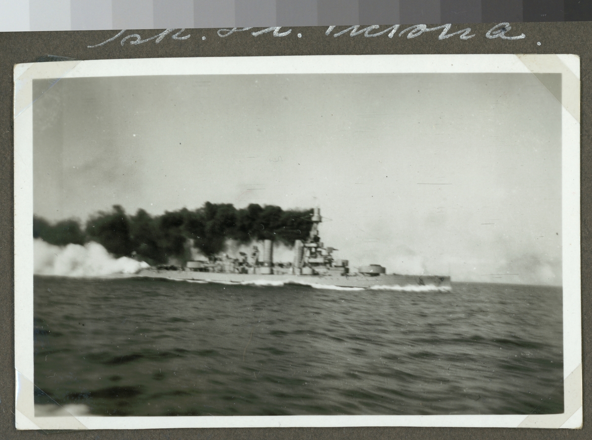 Bilden visar pansarskeppet Drottnings Victoria till sjöss. Svart rök bolmar ur skorstenen och kanonerna i bak har precist avlossats.