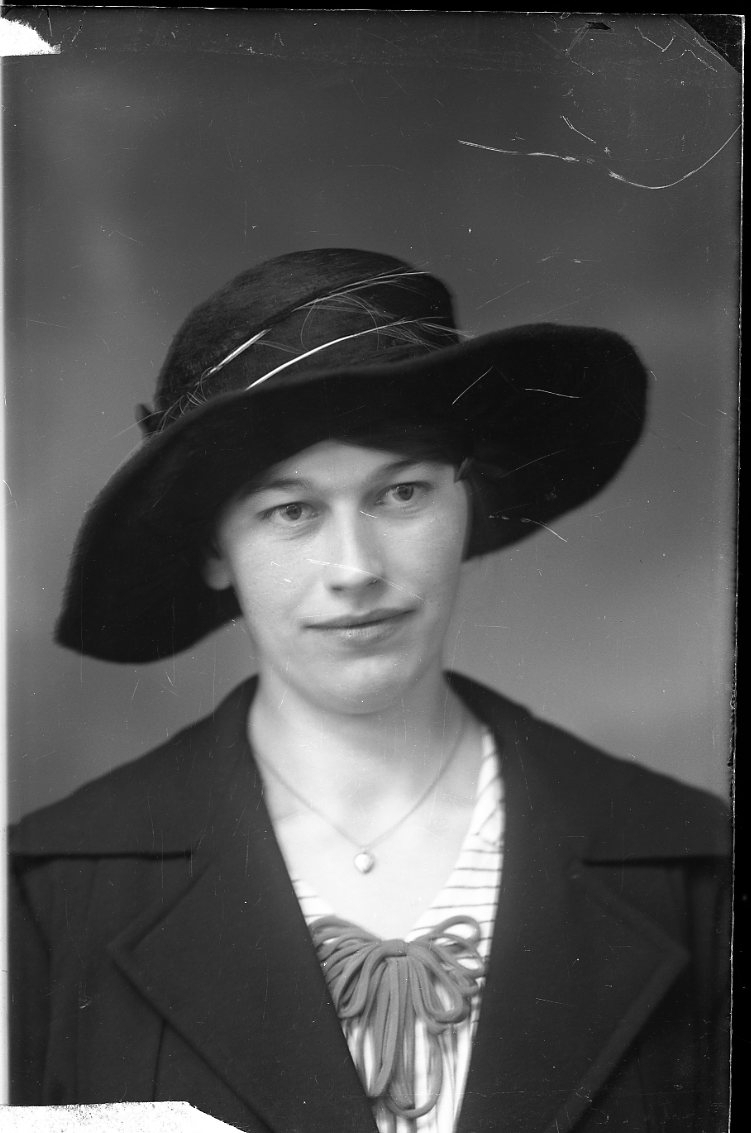 Porträtt av en kvinna i mörk stor hatt.