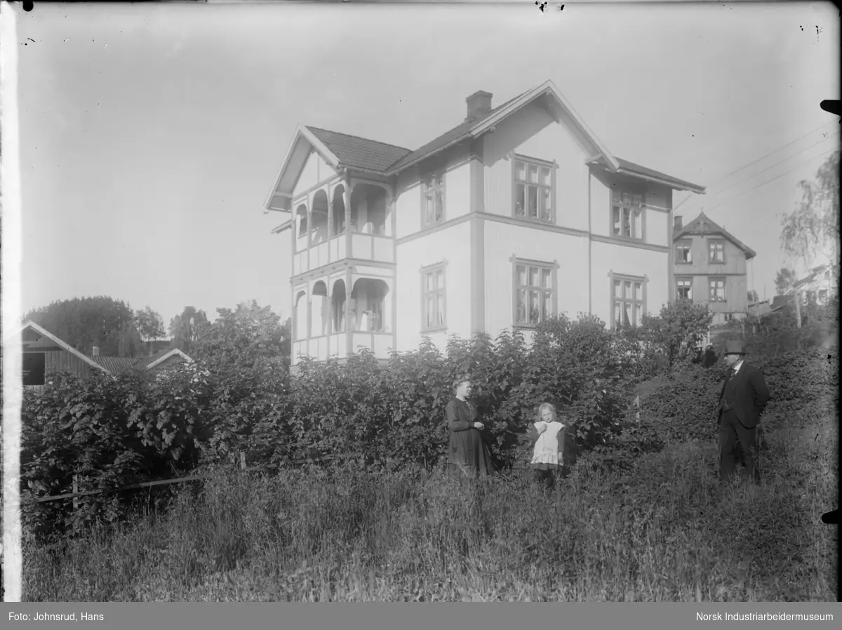 Tre personer foran hus i Tinneveien 13. Tidligere tilhørt kemner John Næset. Flere bygninger synlige i bakgrunnen.