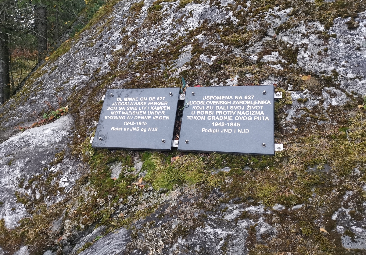 Minnesmerke ved Knutlia rasteplass i Elsfjord (Vefsn). To steinplater er montert på fjellveggen. "Til minne om de 627 jugoslaviske fanger som ga sine liv i kampen mot nazismen under bygging av denne vegen 1942–1945. Reist av JNS og NJS."
