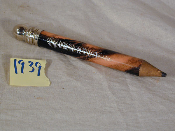 Penalhus forma som ein stor blyant. 2 blyntar, ein pennesplitt og ein linjal inni. Penalet er av tre, med skrukort forma som ei kule. Kork av metall.