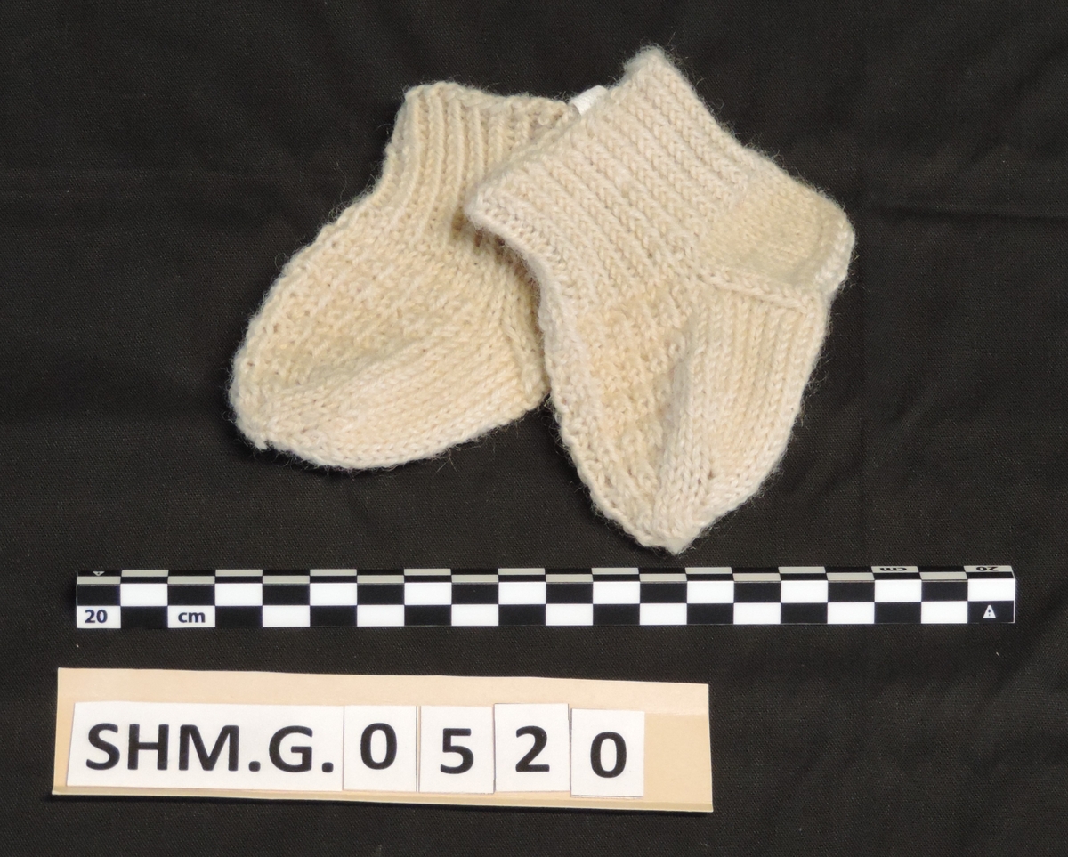 1 par babysokker strikket i hvitt ullgarn med mønster over vristen