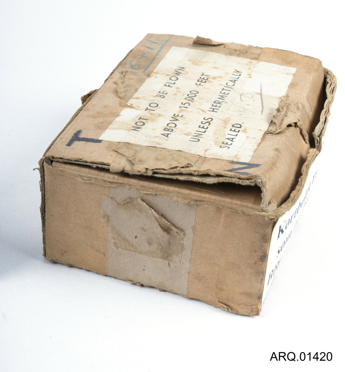 Eske/Emballasje for radiosender "Sweetheart" Det står en tekst på etiketten om at en ikke må fly over 15,000 fot uten at radiosenderen er hermetisk pakket.