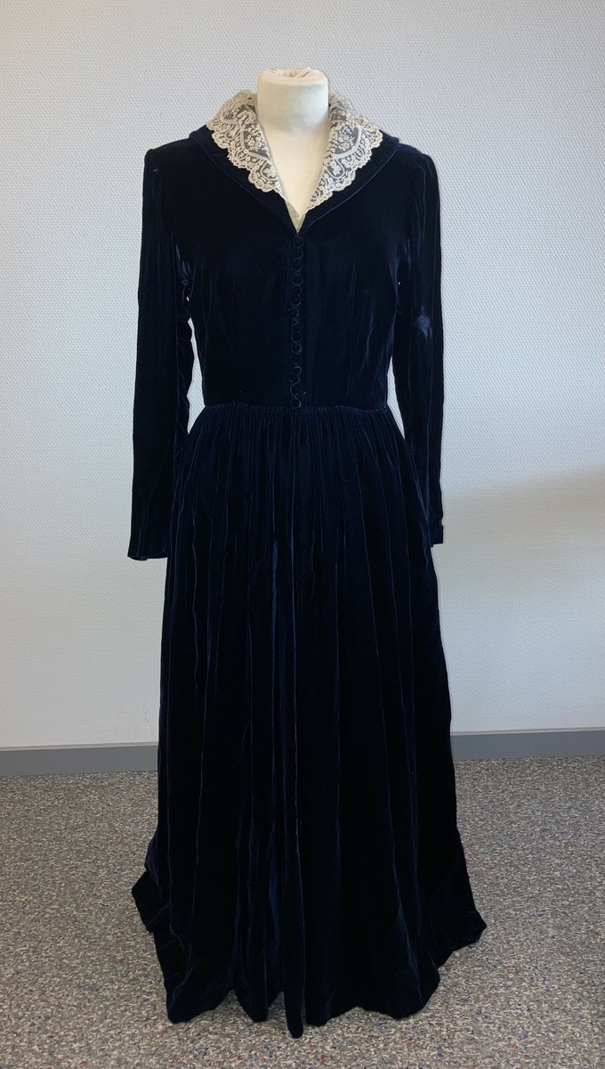 Den mørkeblå kjolen er datert til 1930-årene. Den ble sydd for Hedvig Sverdrup-Thygeson.
Det fortelles at kjolen er laget av den første viskosefløyelen produsert av cellulose fra trevirke som kom fra trevarebedriften Stangeskovene. Hedvig Sverdrup-Thygesons mann var aksjonær i Stangeskovene, og alle aksjonærkonene fikk noen meter av dette stoffet. Det er en sterk familiær tilknytning til Stangeskovene da selskapets grunnlegger, Nils Anker Stang, var Hedvigs morfar.
Ifølge etterkommere av kjolens første eier er kragen laget av italienske kniplinger.
