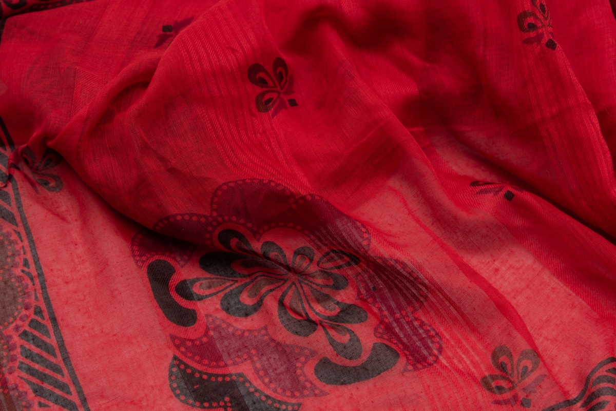 En afrikansk mangemønstret og mangefarget kjole og et rødt sortmønstret skjerf. 
Kjolen ble brukt av Torild Skard da hun var UNICEFs regiondirektør for Vest- og Sentral-Afrika i perioden 1994-98. I Kvinnemuseet samling inngår også foto av Torild Skard på jobb med denne kjolen og skjerfet.