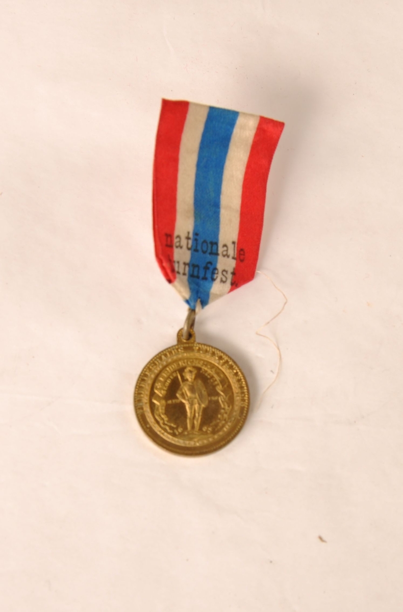 Medalje til Edv. Thoresen fra det første norske nasjonale turnstevnet 15. juni 1886. Henger i et bånd med de norske fargene og påskriften Første norske nationale turnfest.