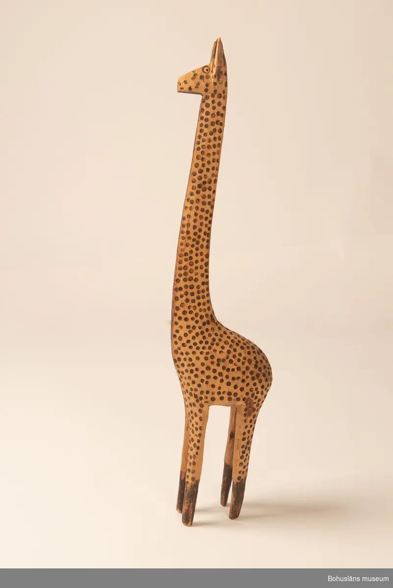 Ur handskrivna katalogen 1957-1958:
Träskulptur; giraff.
H. 69 cm.
de mörka fläckarna istämplade m. ngt. brännjärn. Hel. Infödingsarbete, Sydafrika.

Lappkatalog: 9
