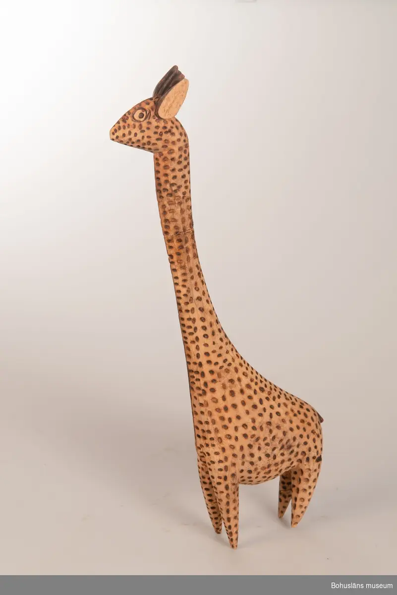 Ur handskrivna katalogen 1957-1958:
Träskulptur; giraff.
H. (utan huvud) 36 cm
de mörka fläckarna istämplade m. ngt, brännjärn.
Huvudet b) avbrutet, L.16,5 cm.
Infödingsarbete, Sydafrika.

Lappkatalog: 9