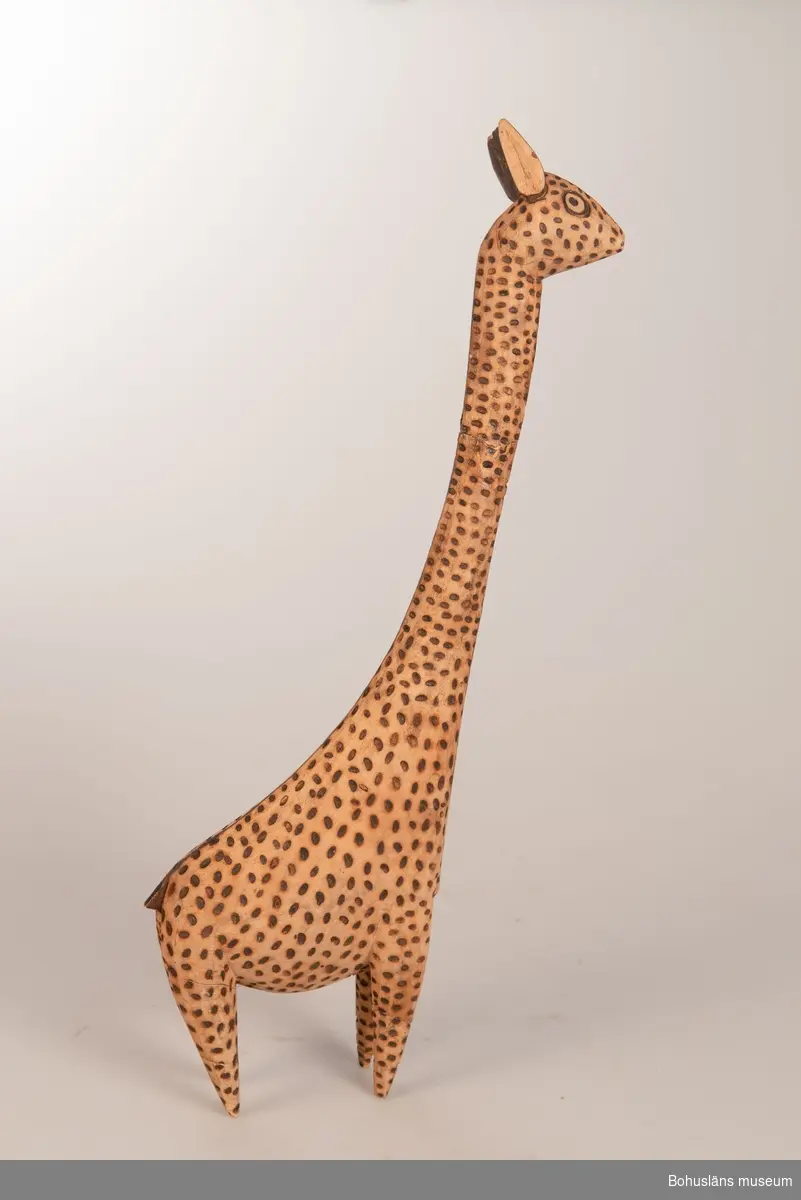 Ur handskrivna katalogen 1957-1958:
Träskulptur; giraff.
H. (utan huvud) 36 cm
de mörka fläckarna istämplade m. ngt, brännjärn.
Huvudet b) avbrutet, L.16,5 cm.
Infödingsarbete, Sydafrika.

Lappkatalog: 9