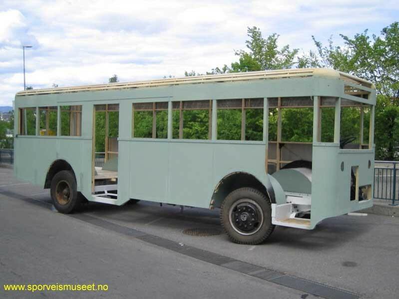 Grønn buss med manglende interiør og vinduer. Bussen har to åpninger til dører, en i front og en i midten.