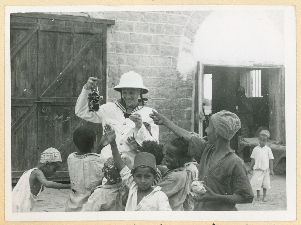 En besättningsmän från kryssaren Gotland visar upp en fotokamera för barn i Ghana.