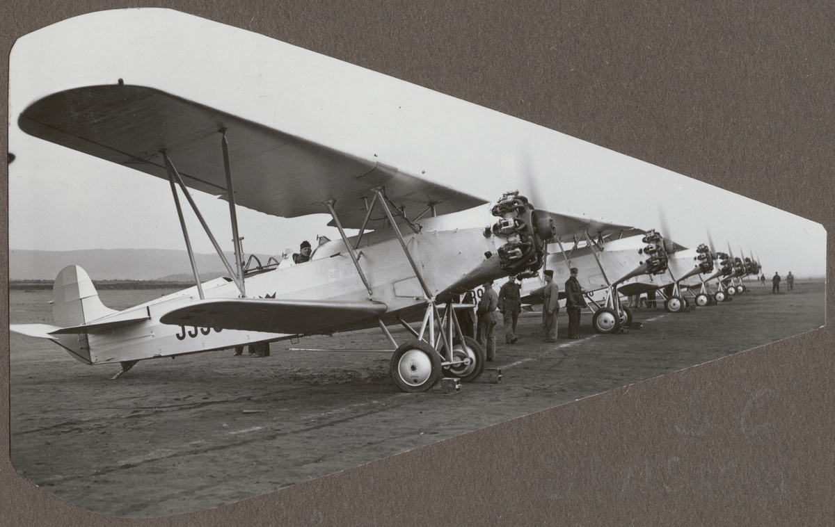 Sex flygplan S 6, Fokker C. VE står på linje på ett flygfält, cirka 1932-1933. Under motorkörning. Flygmekaniker vid flygplanen.