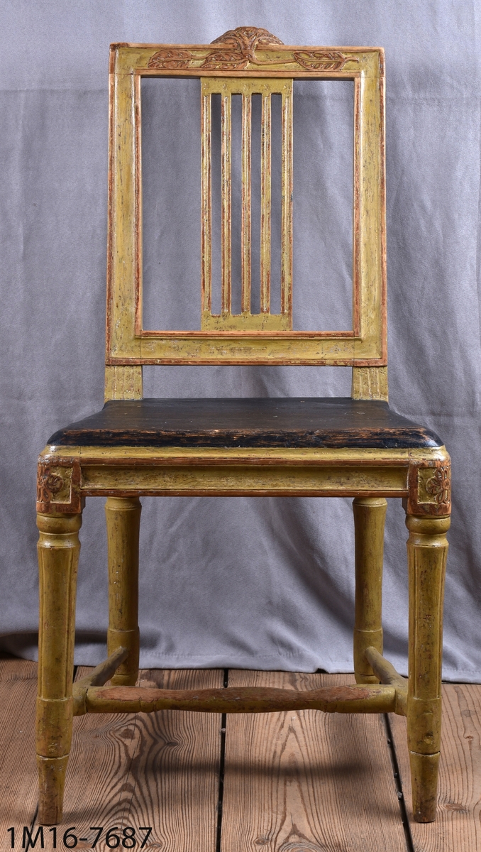 Gråmålad gustaviansk stol med svart sits, svarvade ben med kannelyrer, svarvat benkryss.Genombruten rygg med 4 st spjälor, skuret krön med blomm och bladmönster.