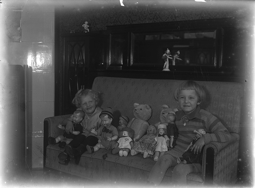 Två småflickor sitter i soffa med sina dockor och nallar. Västerås.