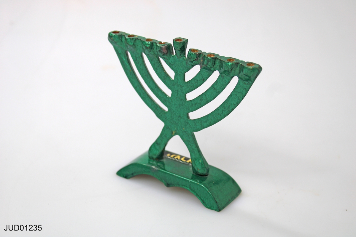 Liten prydnadsljusstake i grön metall. Text på hebreiska ("Chanucka" på foten och "Israel" på botten).