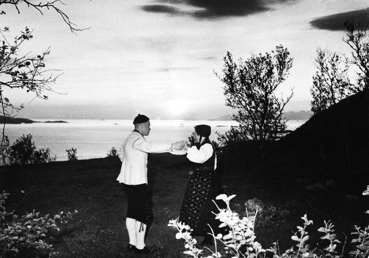 Par ikledd numedalsbunad opptrer med folkedans for midnattssol-passasjerer på Turisthytta på Rønvikfjellet.