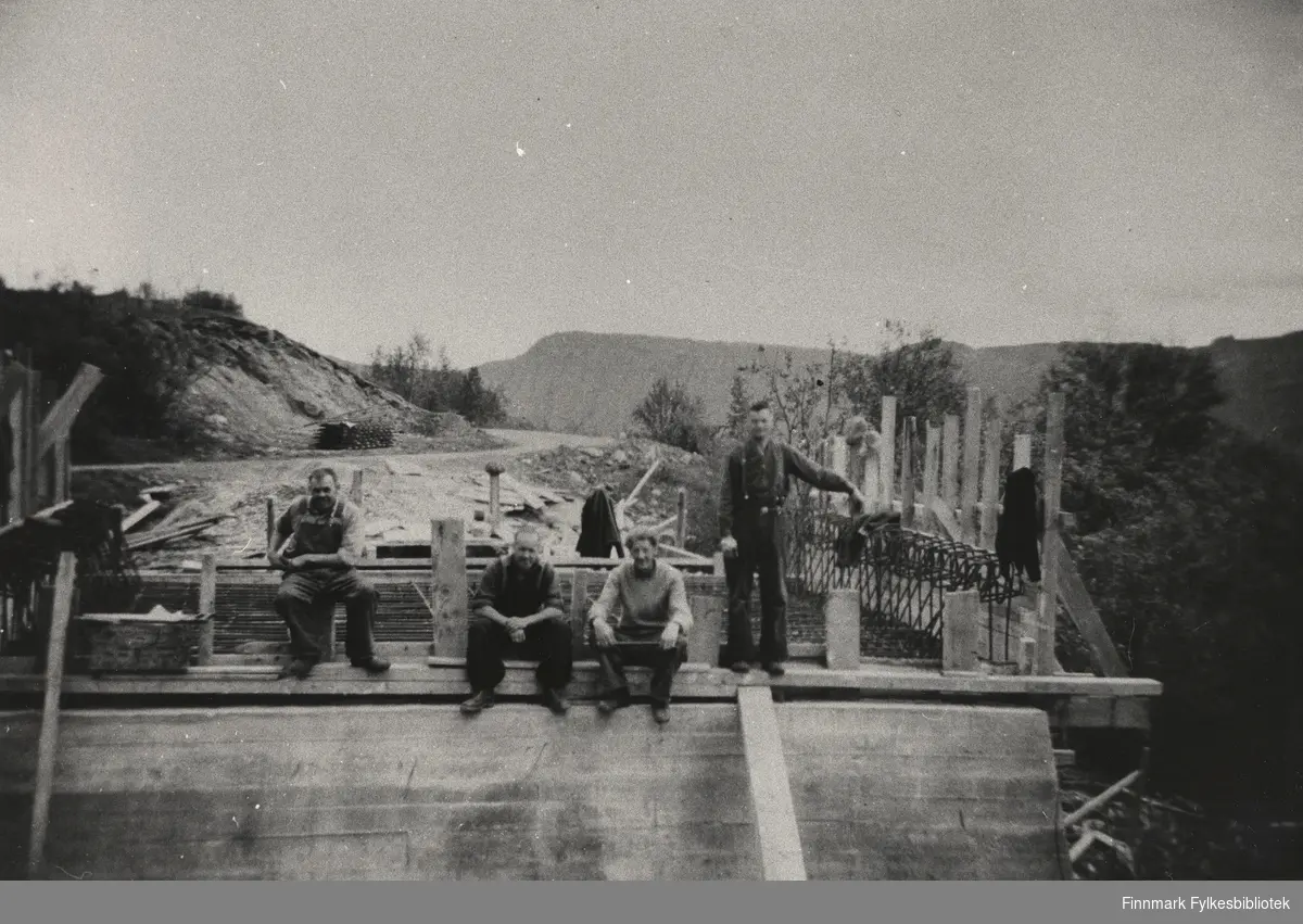 Krigsskadeutbedring i Finnmark. Fire menn sitter på en påbegynt bru ved Gilas i Tana (rundt 1948?).