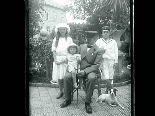 Fotografi taget i Mathilda Ranchs trädgård av en man i uniform med tre barn och en hund, Varberg, kv Bagaren, Prästgatan.