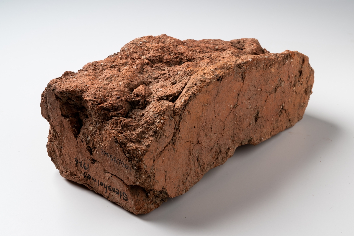 Tegelsten av rödbränande lera, skadad rektangulär form.