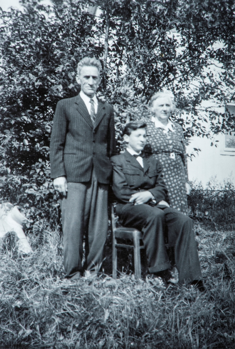 Gruppe 3. Johannes og Gunda Løvås sammen med barnebarnet Willy Erland Løvås, ved Willys konfirmasjon. Bildet er tatt i hagen ved småbruket Løvås i Stange.