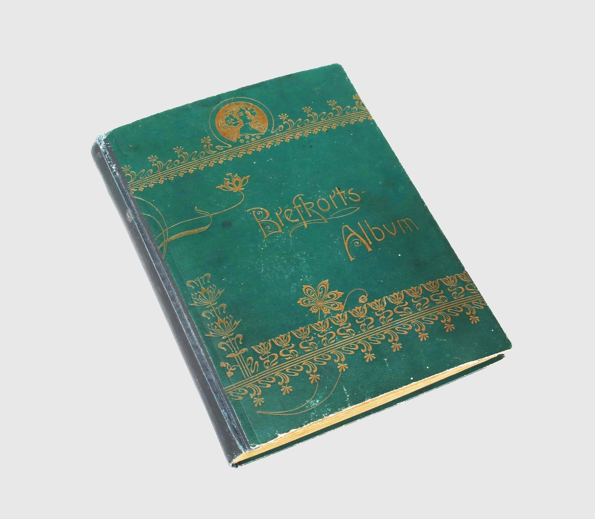 Album för brev- och vykort. Pärmen blågrön, med förgylld präglingsdekor, av blom- och bladbårder upptill och nedtill. Upptill, även med porträttbild av kvinna inom medaljong. I mitten texten: "Brefkorts-Album". Ryggen svart. Albumet har 24 blad. Varje blad med 4 olika kort.
Allt från julkort, påskkort, gott nytt årkort, pingstkort, stadskort, landskapskort m.fl.