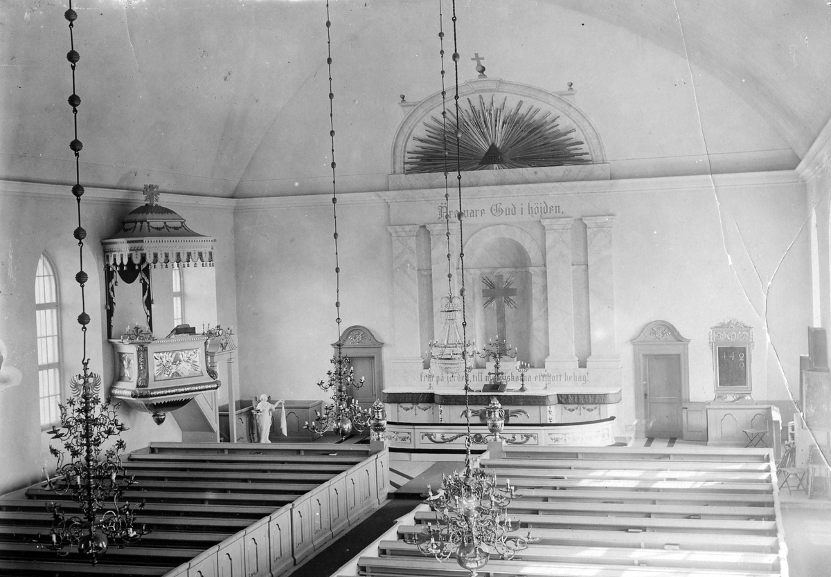 Interiör av okänd kyrka. Uppifrån orgelläkaren ser vi ner mot altaret, altarringen, predikstolen (till vänster) och ljuskronor.