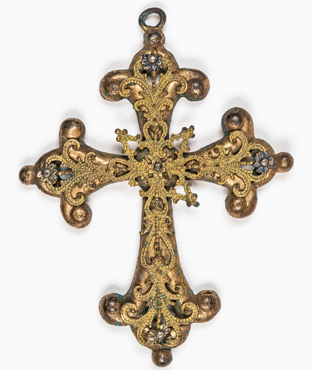 Kors av färgad metall med imiterande filigransarbete.