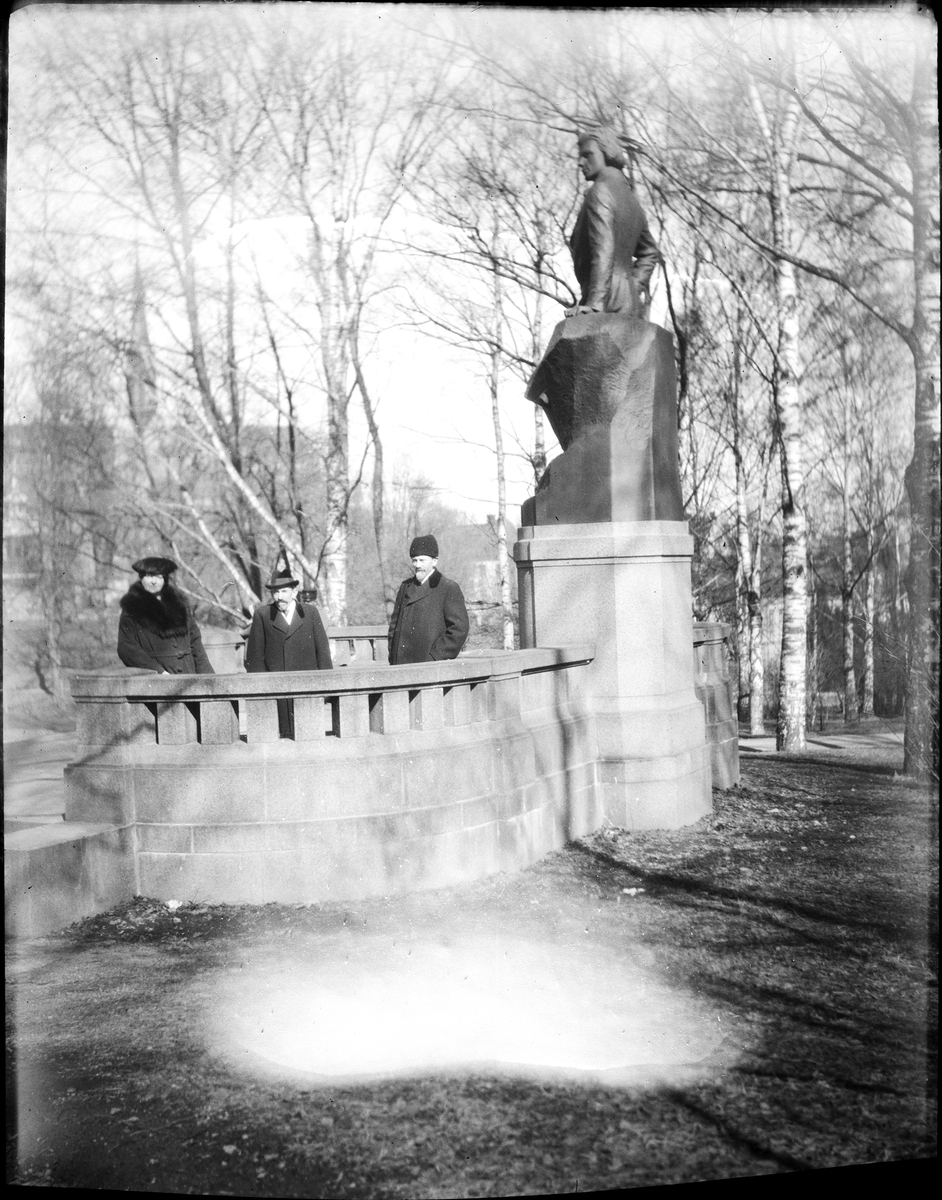 Tre personer vid staty av Gunnar Wennerberg, Slottsbacken, Uppsala påsken 1923