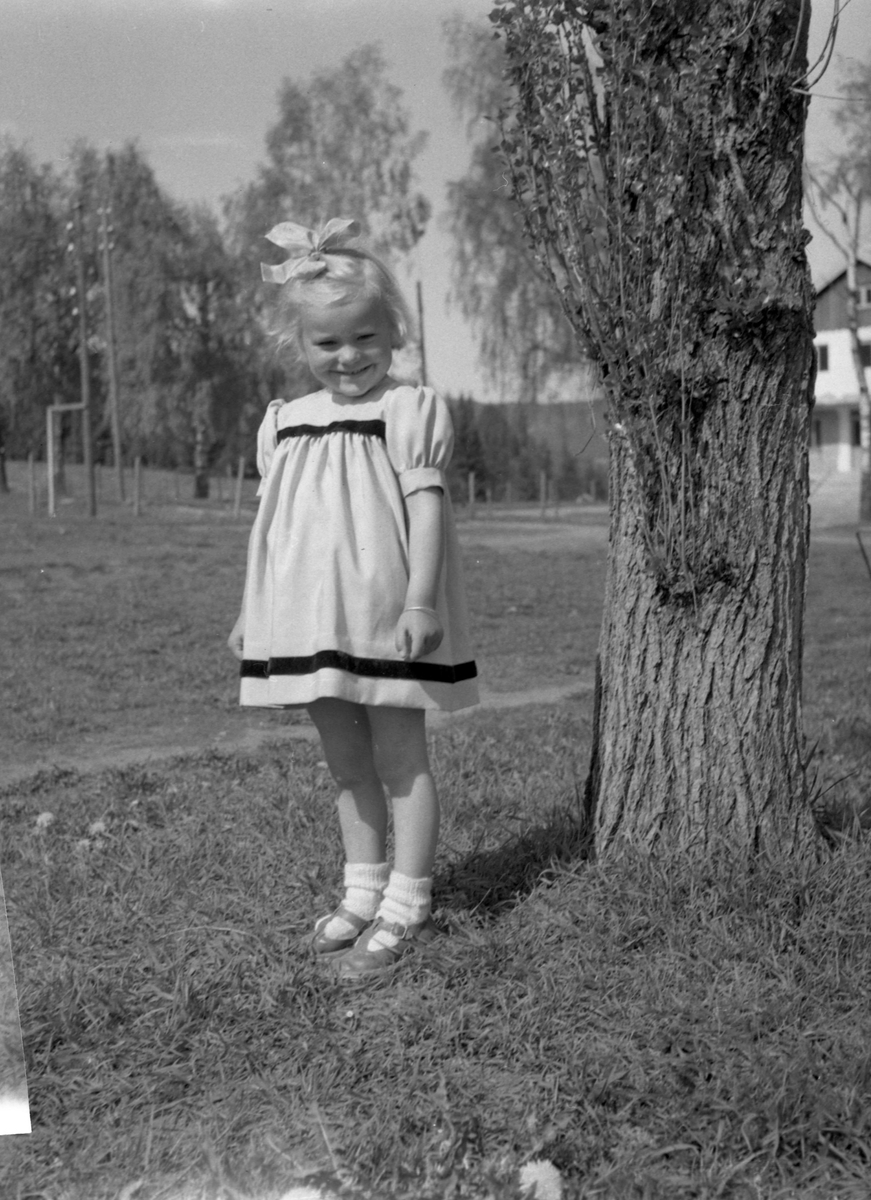 liten jente står ved et tre