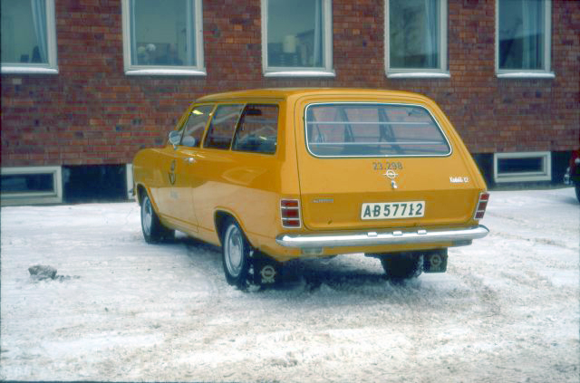 Bilen fotograferad snett bakifrån, vänster sida. Bakluckan, som är
nedfälld, har beteckningen "Kadett 12". Plats: Gården vid Postens
Industrier i Ulvsunda.