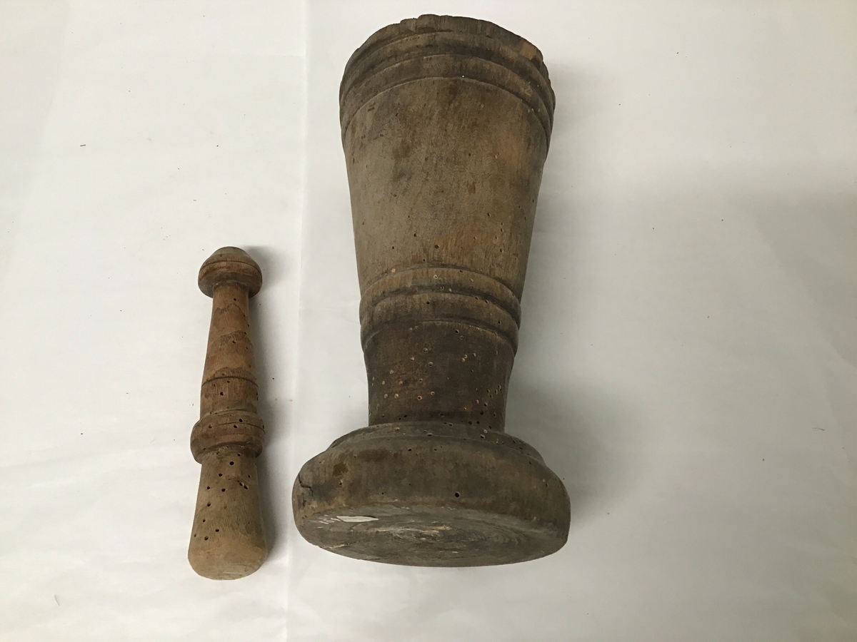 Både mortar og pistill er laga av tre, mortar er sylinderforma svakt kon  med stett. Mortaren har ein skade øvst i munning.