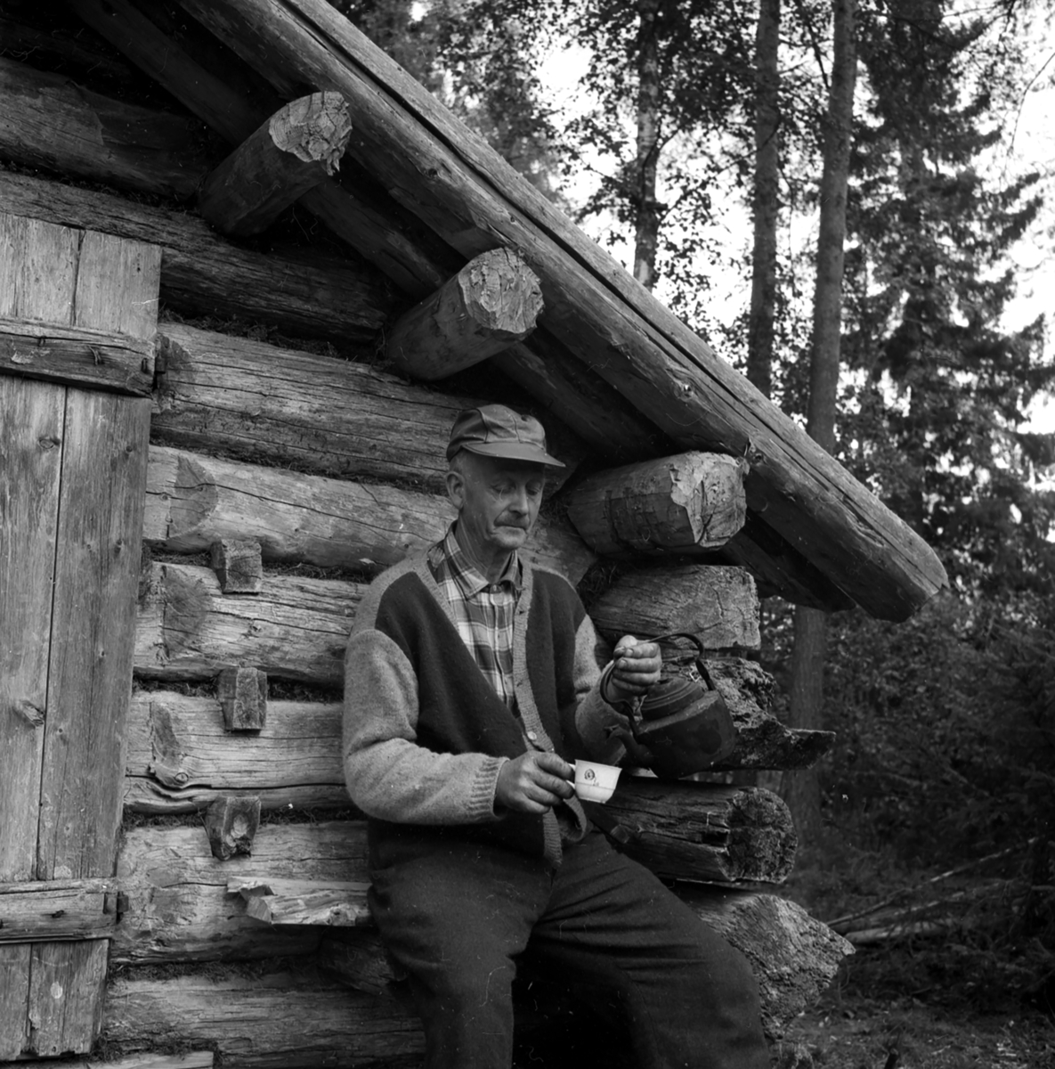 Fra Norsk Skogbruksmuseum/Skogmuseum.
En mann sitter ved koia.