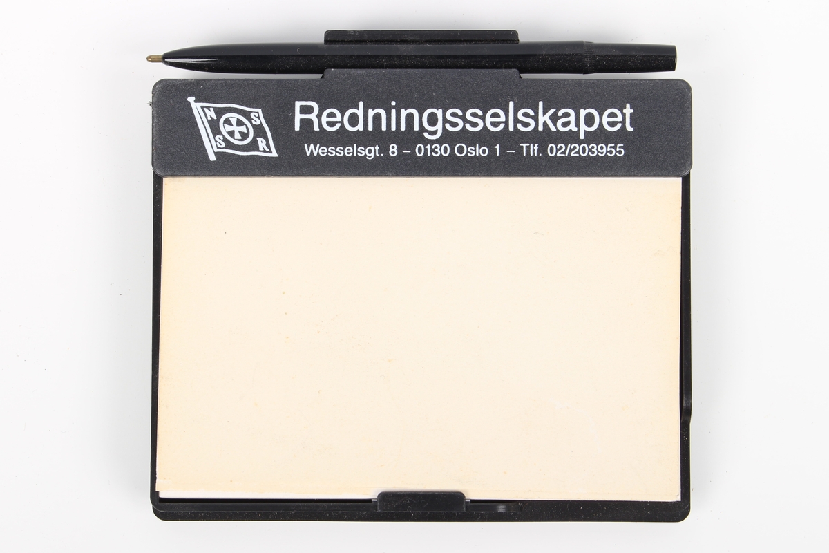 Reklameartikkel fra Redningsselskapet: notatblokk i holder, med penn.