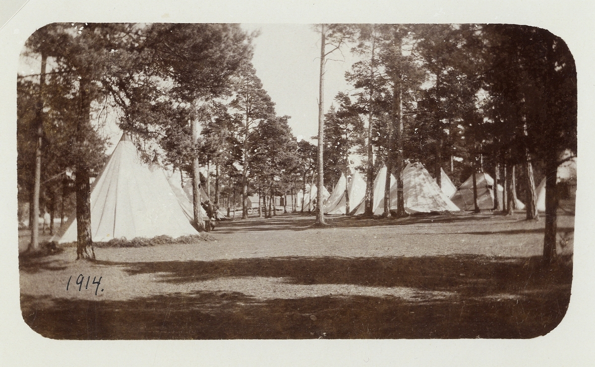 Ett antal militärtält på Kronobergshed,1914. Bland tälten skymtar några meniga.