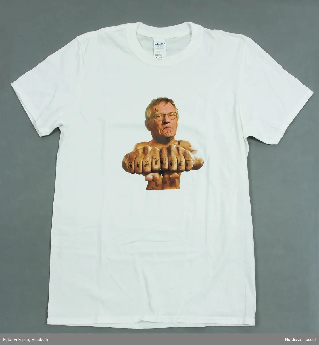 Vit t-shirt med färgtryck med portträttbild av Anders Tegnell, statsepidemiolog vid Folkhälsomyndigheten under Coronapandemin 2020-2021, samt texten "Stay home".
/Anna Fredholm 2021-12-09